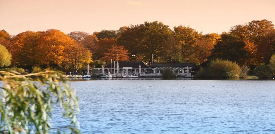 ... Herbstlandschaft am See mit Gebäude im Hintergrund